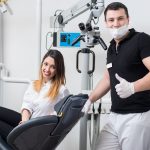 Handsome male dentist with attractive female patient in modern dental office